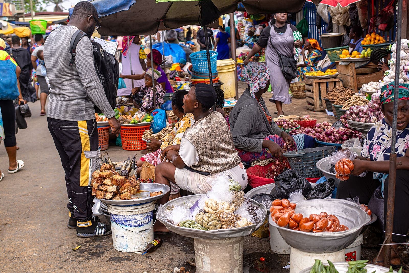 Traders and customers among produce stalls at a market in Ghana.